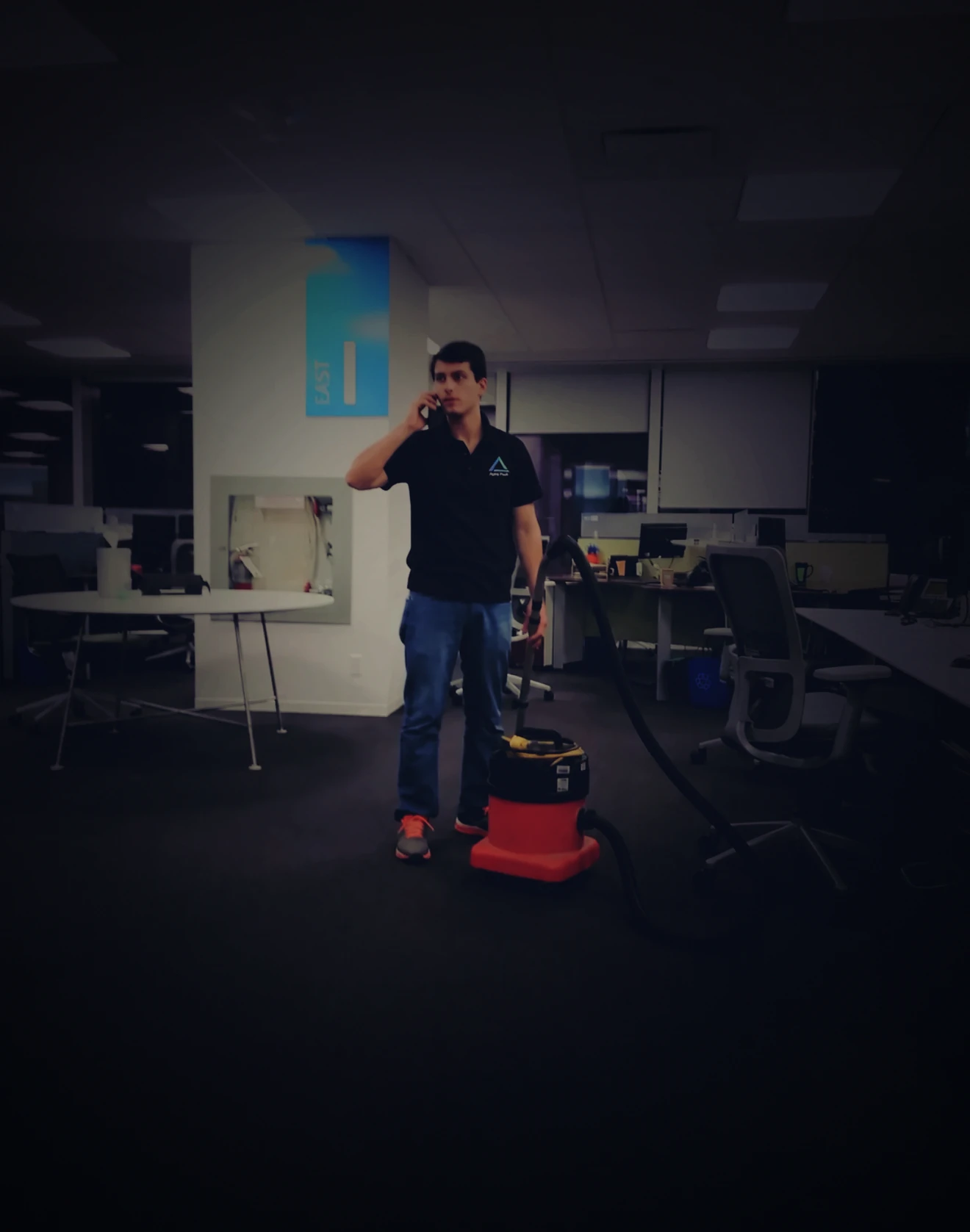 An Alpha Peak team member vacuuming an open-plan office
